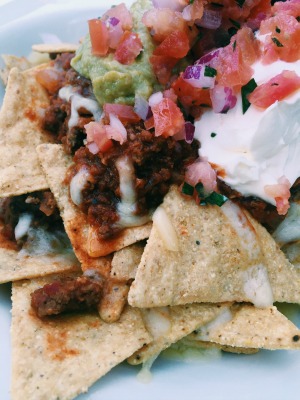 baked nachos topped with pureed avocado,chopped tomatoes,cheese,sour cream and beef
