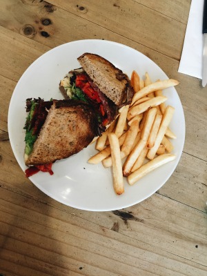 a substantial sandwich filled with veggies and fresh beef, accompanied by fries